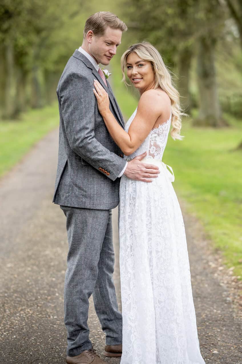 Couple in wedding attire embracing outdoors.