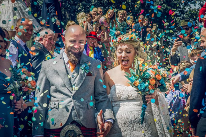 Joyful wedding couple with confetti celebration.