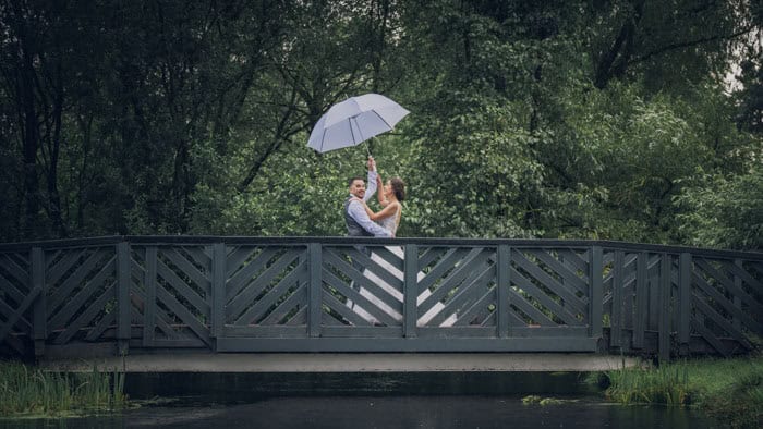 Couple with umbrella on bridge in rainy weather