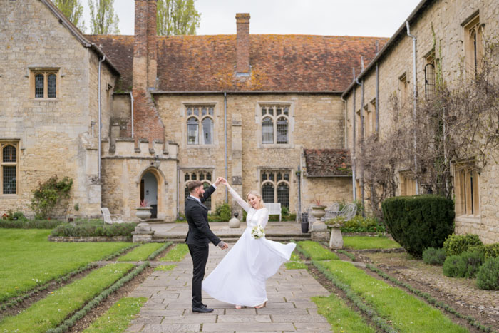 Bride and groom dancing outside historic British manor.