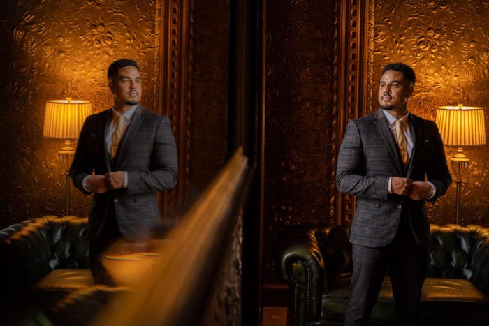 Man in suit by mirror in elegant room.