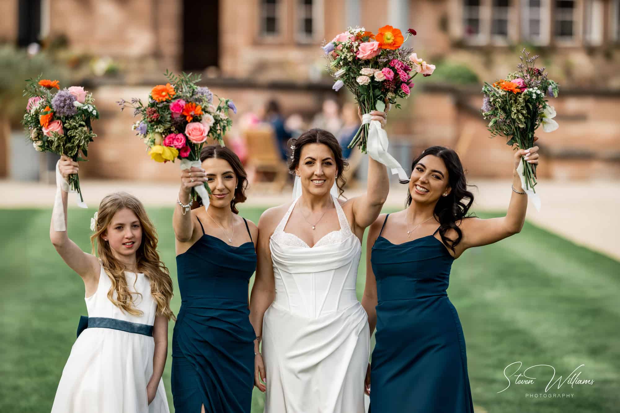 Bride and bridesmaids holding bouquets aloft