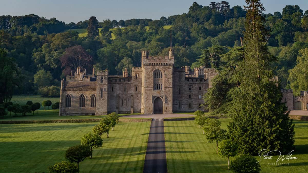Historic stone castle with long tree-lined driveway